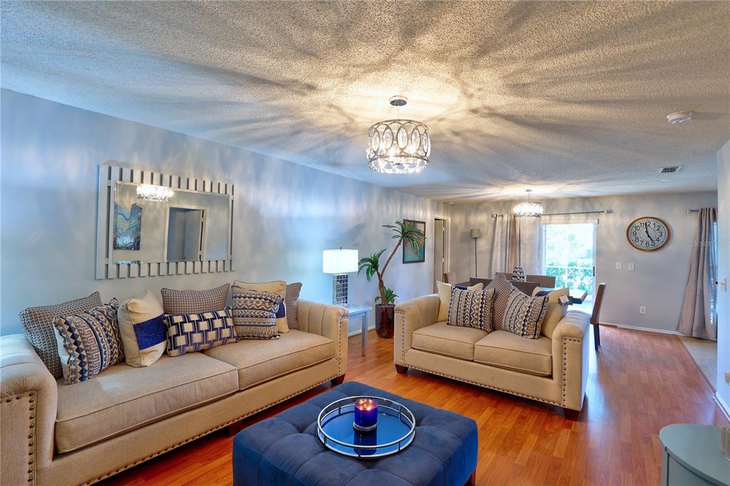 A living room features two beige sofas, a blue ottoman, and hardwood flooring — 50989 HIGHWAY 27 UNIT 360, DAVENPORT, FL