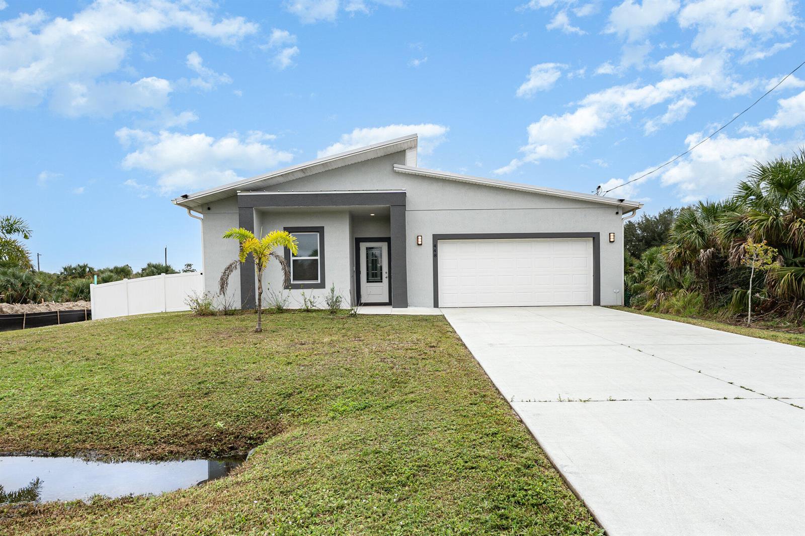 A modern single-story house features a gray stucco exterior, a white garage, and a driveway — 448 Saint Andre Boulevard, Palm Bay FL 32908, PALM BAY, FL