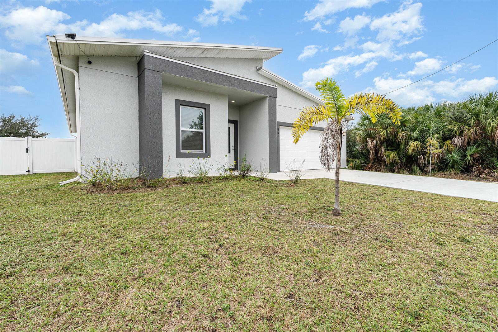 A modern, single-story house with a gray and white exterior sits on a grassy lot — 448 Saint Andre Boulevard, Palm Bay FL 32908, PALM BAY, FL