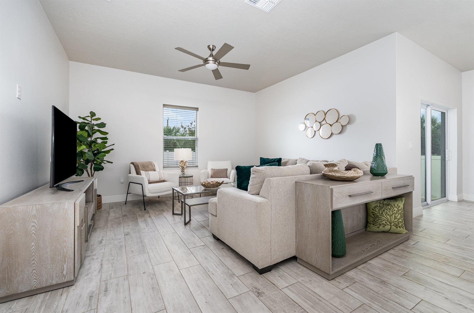 A living room features light wood-look tile flooring, a sectional sofa, and a ceiling fan — 448 Saint Andre Boulevard, Palm Bay FL 32908, PALM BAY, FL