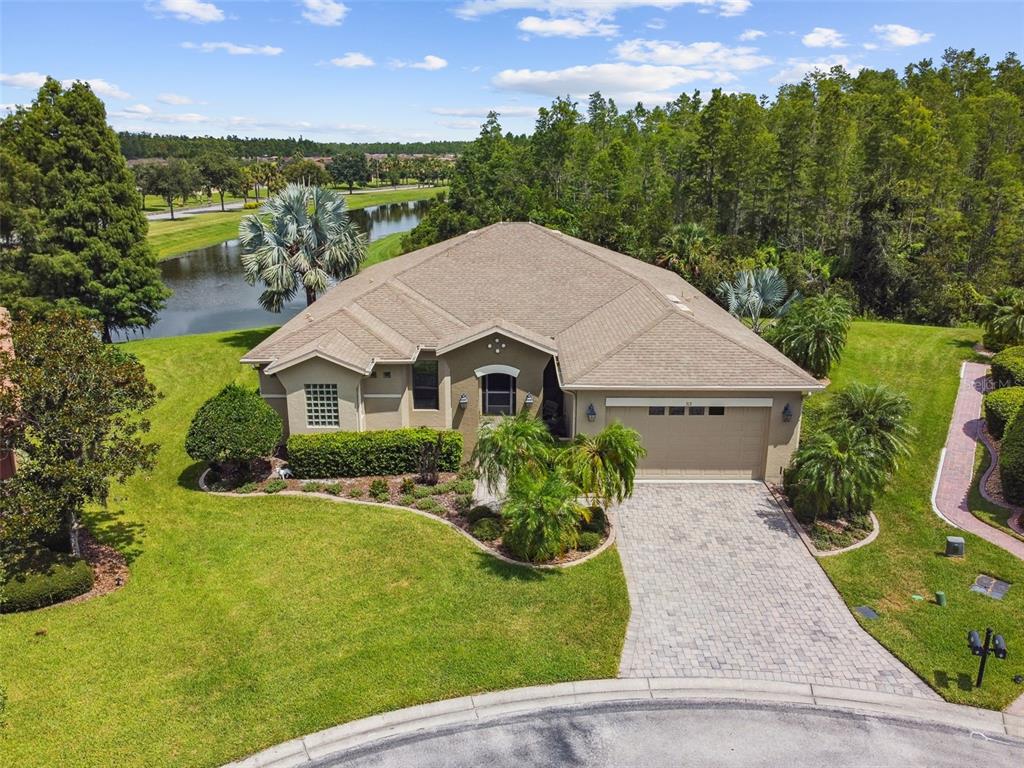 An aerial view of a single-story house with a paved driveway and a pond nearby — 313 SANTA BARBARA LANE, KISSIMMEE, FL