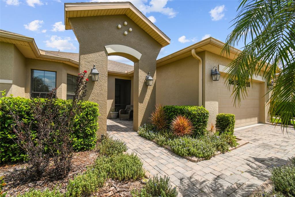 A tan stucco house features a paved walkway, a covered entryway, and a two-car garage — 313 SANTA BARBARA LANE, KISSIMMEE, FL