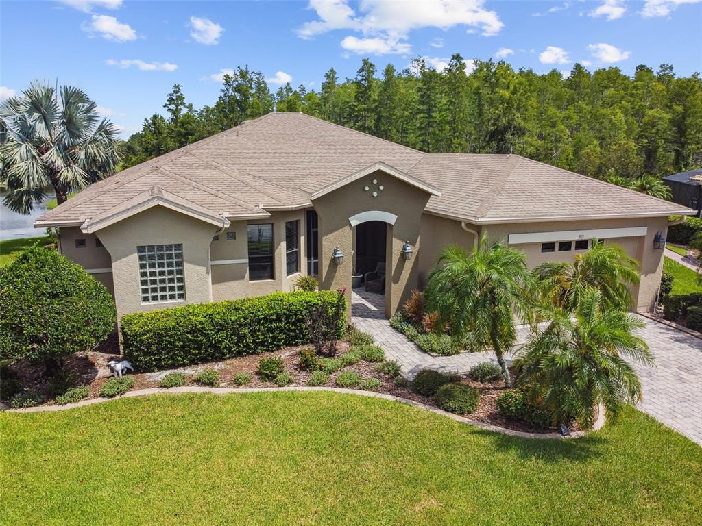 An aerial view of a tan, single-story house with a paved driveway and landscaped yard — 313 SANTA BARBARA LANE, KISSIMMEE, FL