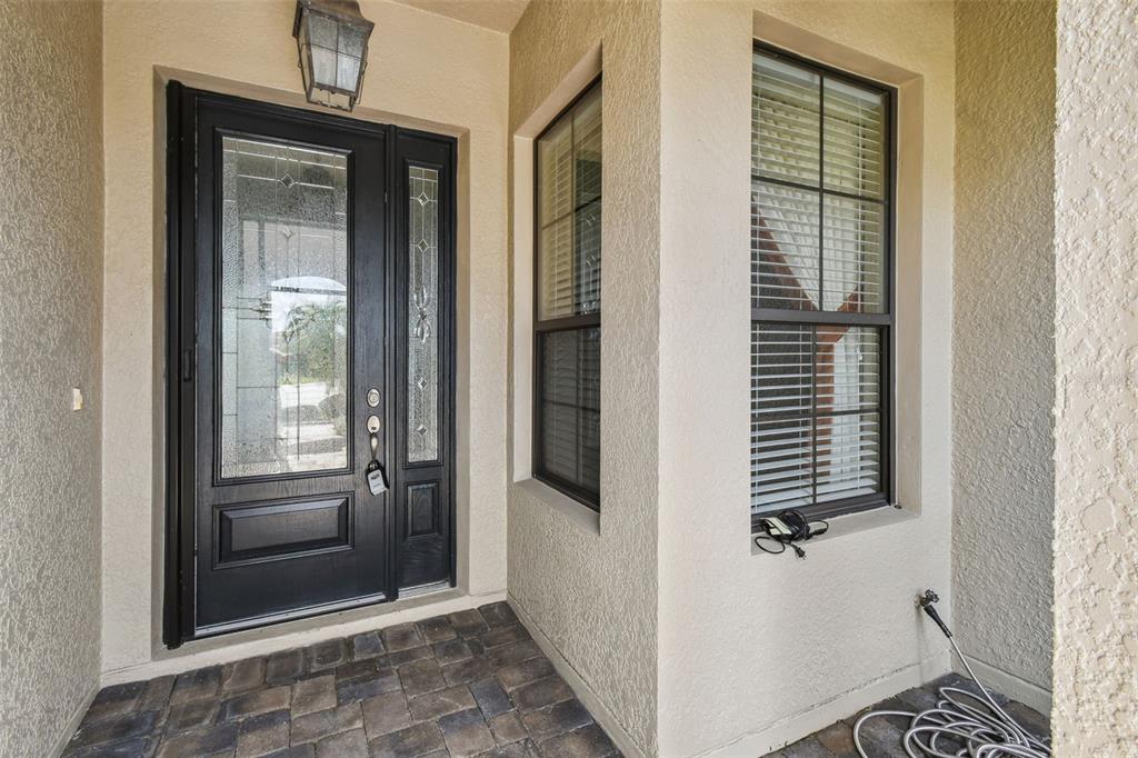 A dark front door with glass panels sits next to two windows on a porch — 313 SANTA BARBARA LANE, KISSIMMEE, FL
