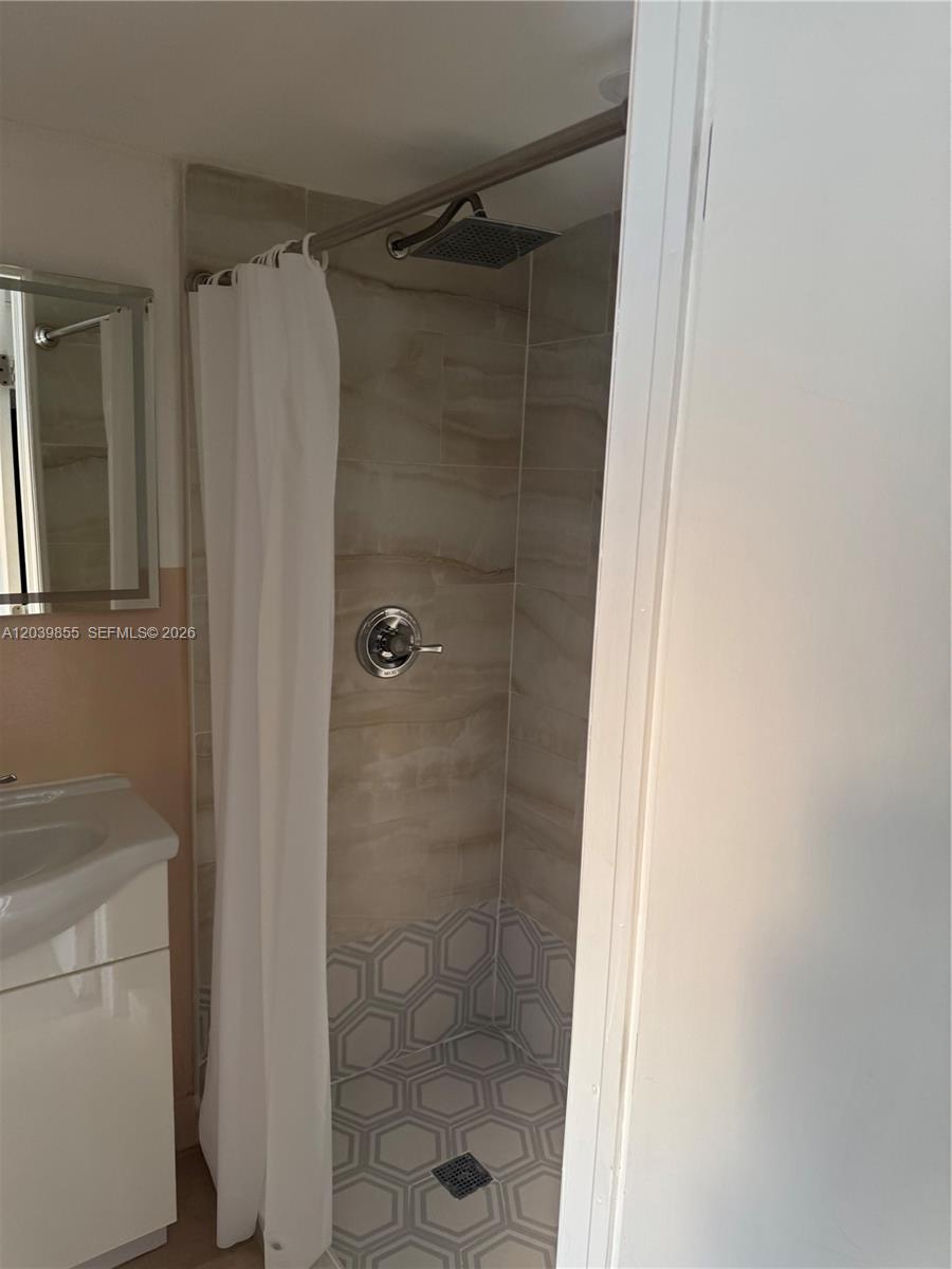 A bathroom features a tiled walk-in shower with a rainfall showerhead and hexagonal floor tiles — MIAMI GARDENS, FL