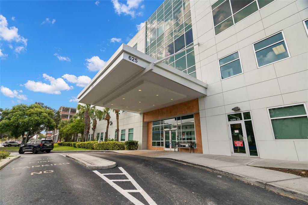 The exterior of a modern office building features a large covered entrance and glass windows — 625 6TH AVENUE S UNIT 405, ST PETERSBURG, FL