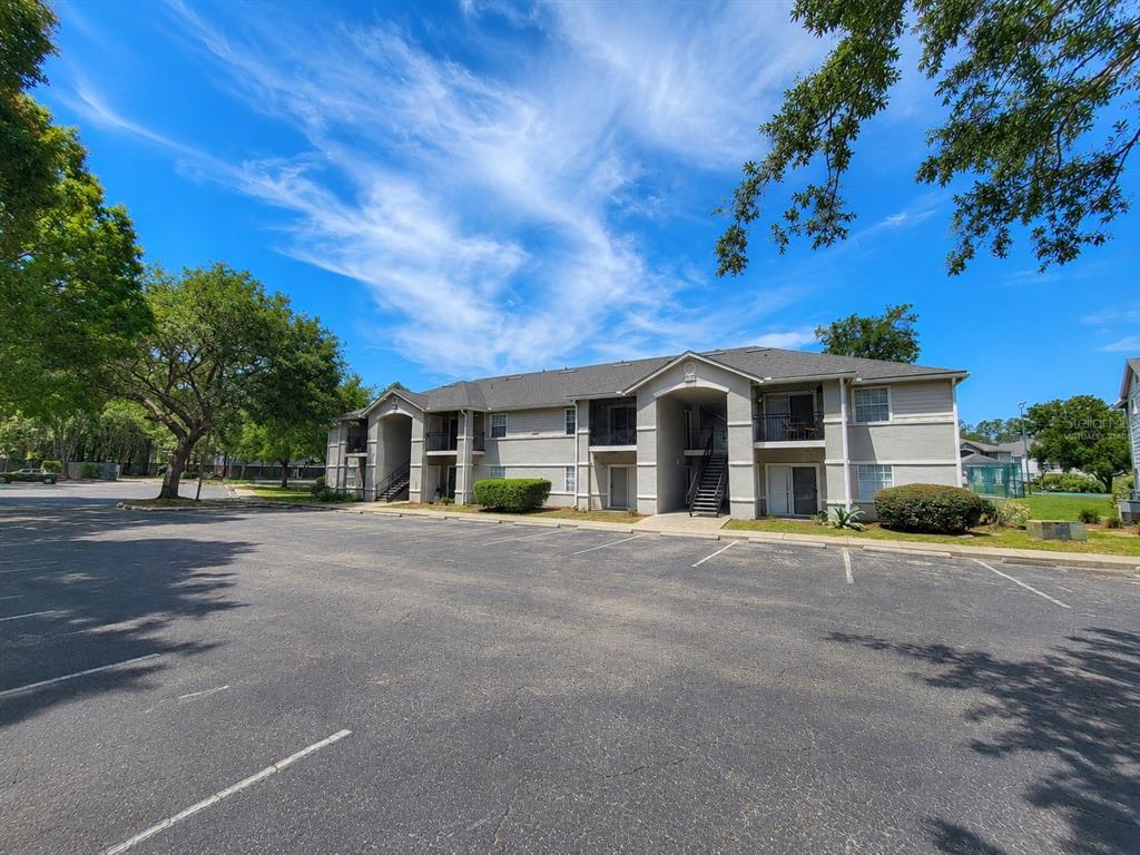 A two-story apartment building with a parking lot in the foreground under a blue sky — 3705 SW 27TH STREET UNIT 818, GAINESVILLE, FL