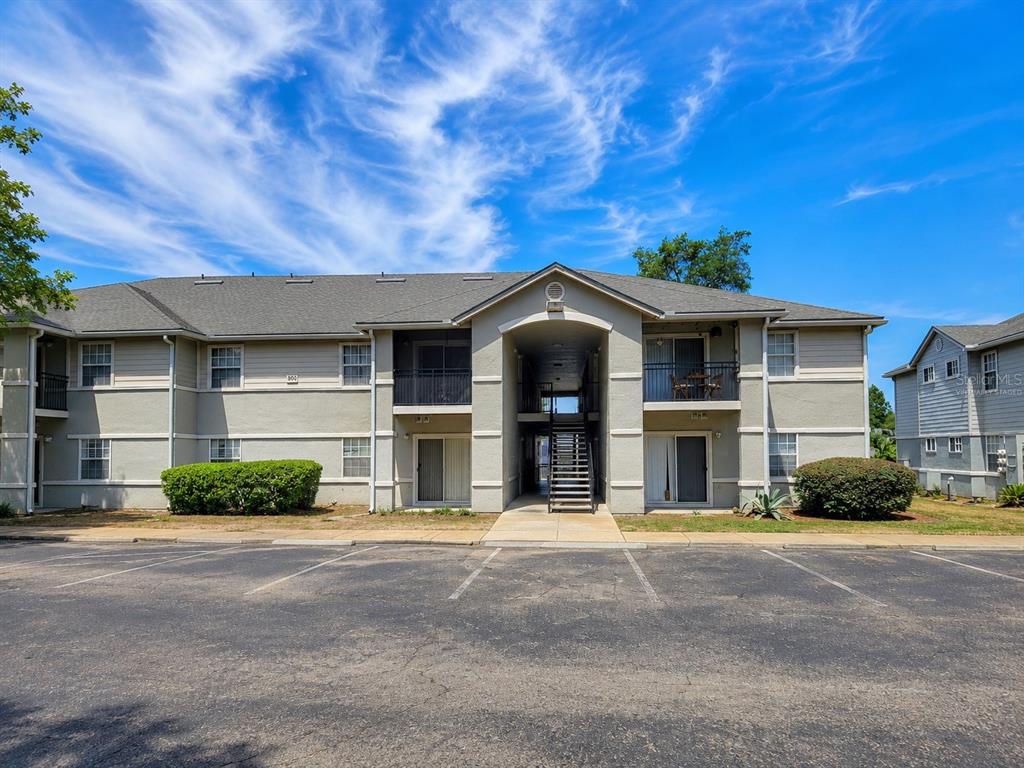 A two-story apartment building exterior with a central staircase and a paved parking lot — 3705 SW 27TH STREET UNIT 818, GAINESVILLE, FL