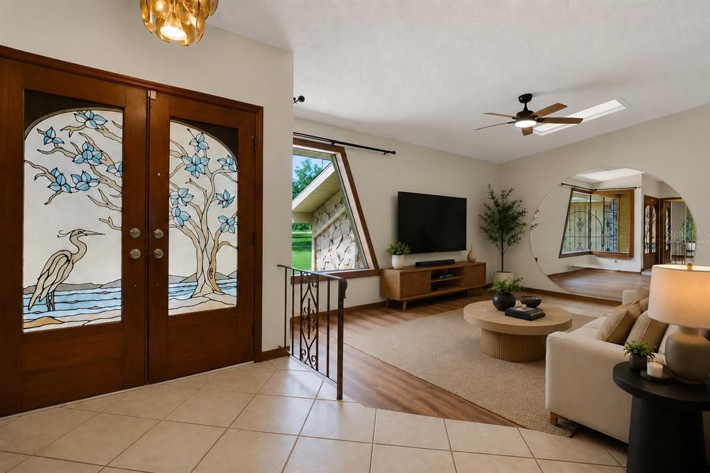 A living room features stained glass double doors, a large circular mirror, and a slanted window — 7488 RIVER COUNTRY DRIVE, WEEKI WACHEE, FL