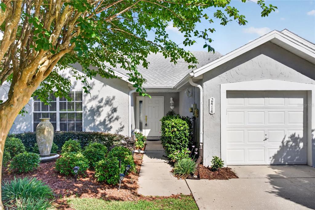 The exterior of a single-story house features a white garage, a front entrance, and landscaping — 2414 SW 20TH COURT, OCALA, FL