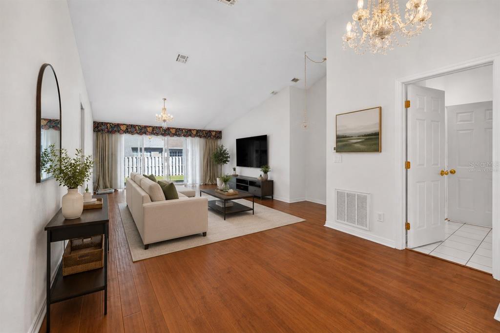 A living room with wood floors, a vaulted ceiling, a sofa, and a television — 2414 SW 20TH COURT, OCALA, FL