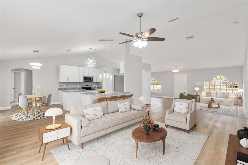 An open-concept living room and kitchen with white cabinetry, light wood flooring, and vaulted ceilings — 4181 SW 111TH PLACE, OCALA, FL