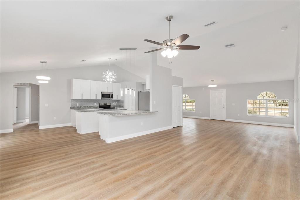 An open-concept kitchen and living area with light wood-look flooring and white cabinetry — 4181 SW 111TH PLACE, OCALA, FL