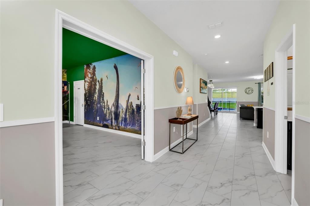 A hallway with marble-look tile flooring leads to a living area with a dinosaur mural — 9194 SOMMERSET HILLS DRIVE, DAVENPORT, FL