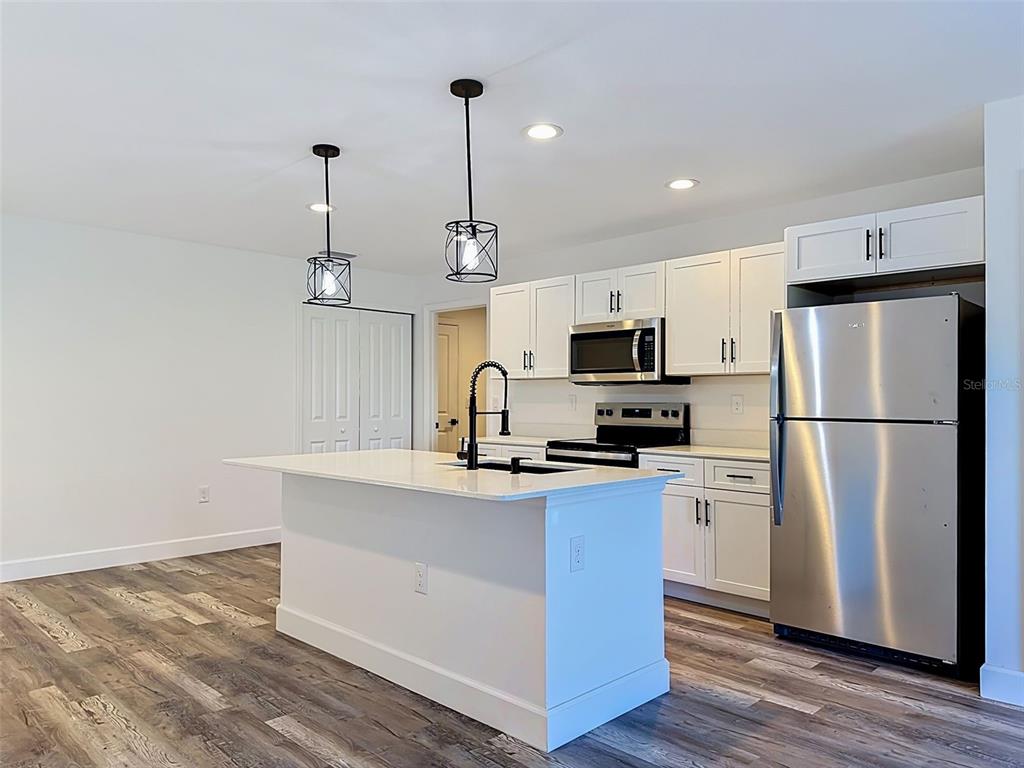 A modern kitchen features white cabinets, a central island with a sink, and stainless appliances — 2715 GISELA RD, NORTH PORT, FL