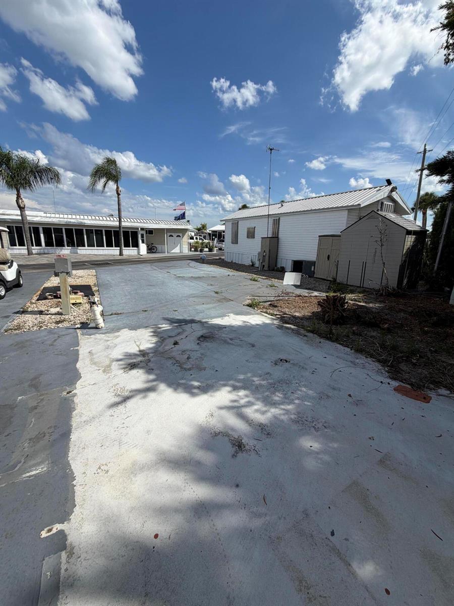 A concrete driveway leads to a white mobile home with a shed under a blue sky — 7950 Fl-78, Okeechobee FL 34974, OKEECHOBEE, FL