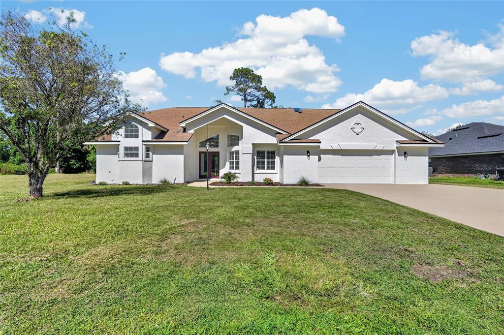A single-story white house with a brown roof and a two-car garage — 107 LINDSAY DRIVE, PALM COAST, FL
