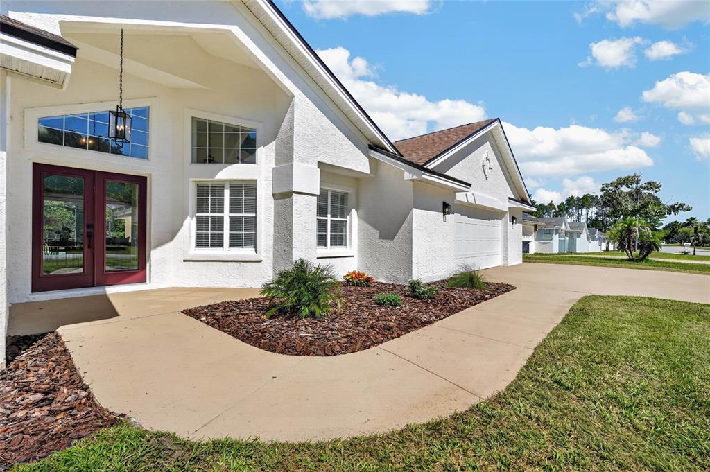 A white stucco house features a red double front door and a concrete driveway — 107 LINDSAY DRIVE, PALM COAST, FL
