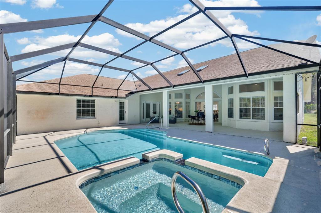 A screened-in patio features a swimming pool, a hot tub, and a covered seating area — 107 LINDSAY DRIVE, PALM COAST, FL