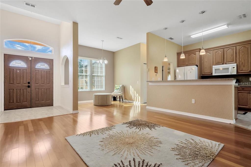 An open-concept living area with hardwood floors, a kitchen breakfast bar, and a front entryway — 503 ANISE COURT, KISSIMMEE, FL