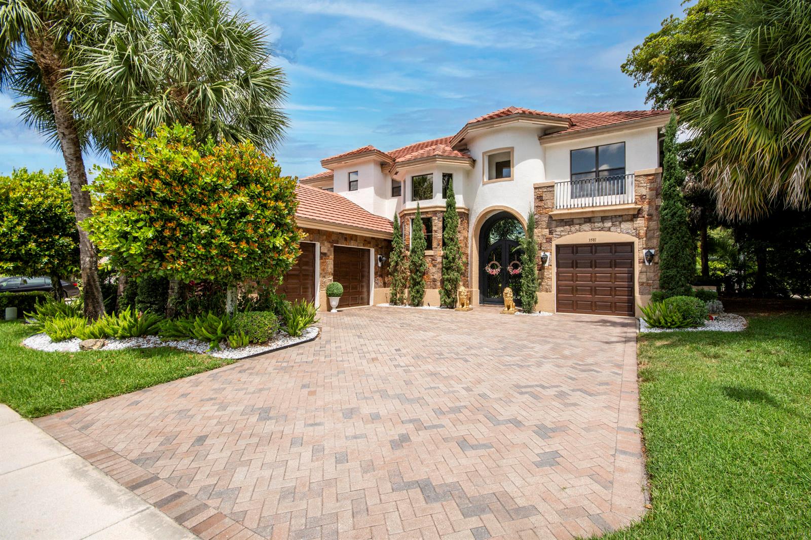 A two-story stucco and stone house with a paved driveway and three garage doors — 3581 Collonade Drive, Wellington FL 33449, WELLINGTON, FL