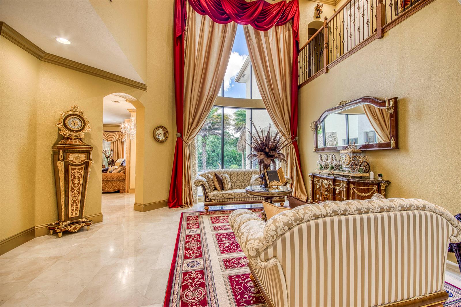 A formal living room features high ceilings, ornate drapes, a grandfather clock, and marble floors — 3581 Collonade Drive, Wellington FL 33449, WELLINGTON, FL
