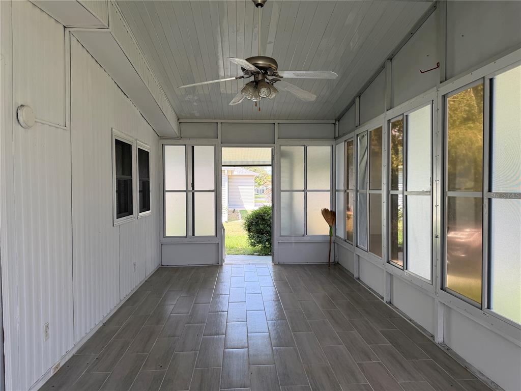 A sunroom with white walls, a ceiling fan, and gray wood-look tile flooring — 925 BEECHWOOD AVENUE, LADY LAKE, FL