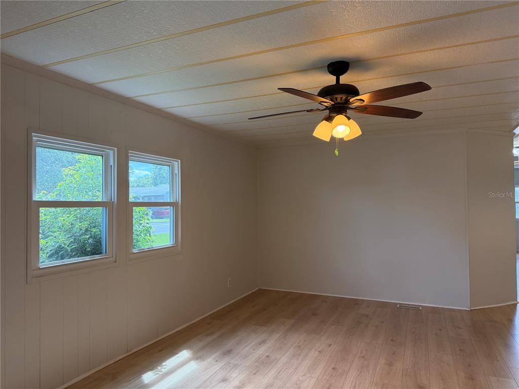 A room with light-colored walls, wood-look flooring, two windows, and a ceiling fan — 925 BEECHWOOD AVENUE, LADY LAKE, FL