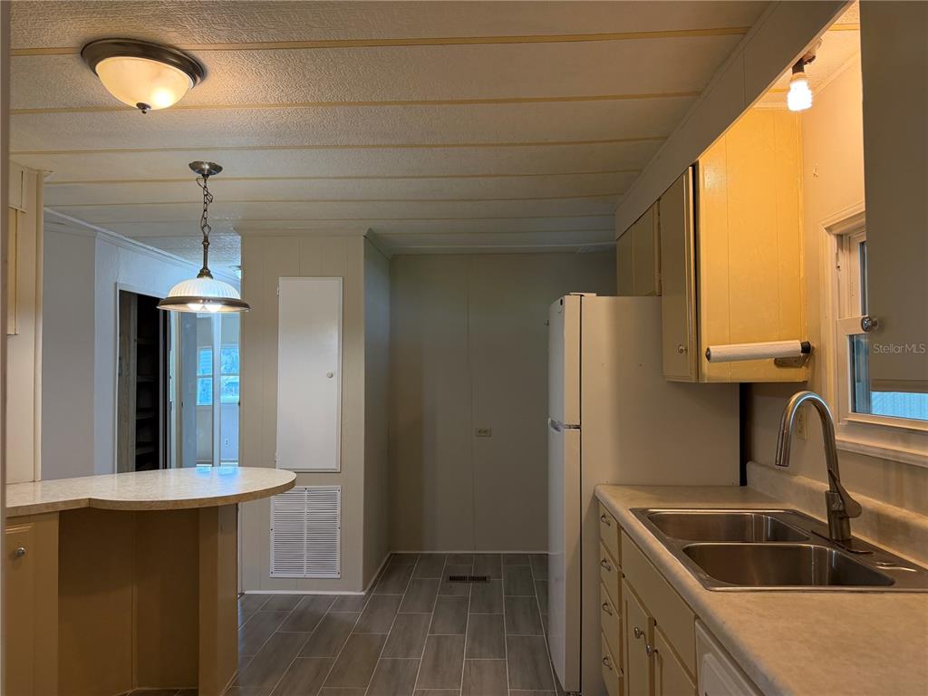 A kitchen featuring light-colored cabinets, a double sink, a white refrigerator, and tile flooring — 925 BEECHWOOD AVENUE, LADY LAKE, FL