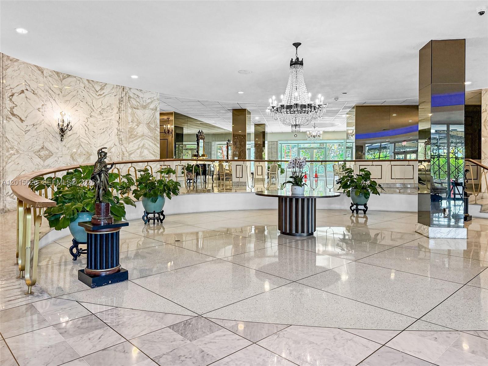 A grand lobby features polished marble floors, a crystal chandelier, and a decorative statue — 5255 Collins Ave, Miami Beach FL 33140, MIAMI BEACH, FL