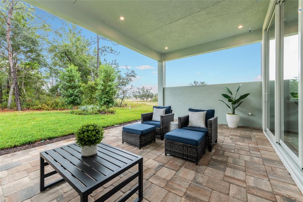 A covered patio with stone pavers, outdoor furniture, and a view of a grassy yard — 1631 LAKE RESERVE DRIVE, DELAND, FL