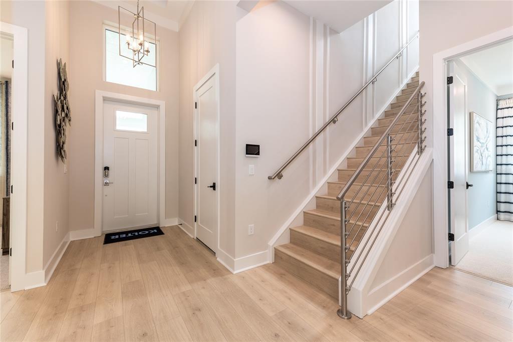 An entryway features light wood flooring, a white front door, and a staircase with metal railings — 1631 LAKE RESERVE DRIVE, DELAND, FL