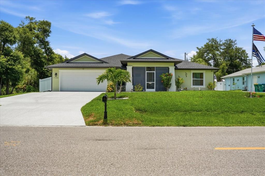 A single-story house with a light green exterior, a two-car garage, and a screened entryway — 17432 SHIRLEY AVENUE, PORT CHARLOTTE, FL