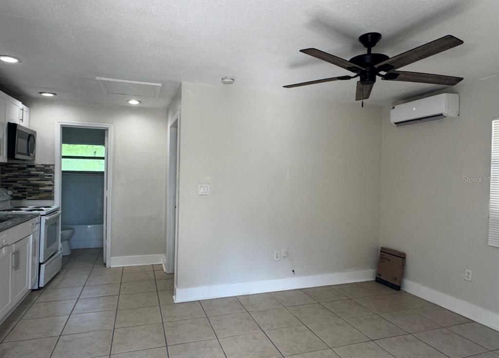 A room with tile flooring, a ceiling fan, and an adjacent kitchen area — 10022 N LANTANA AVENUE UNIT A, TAMPA, FL