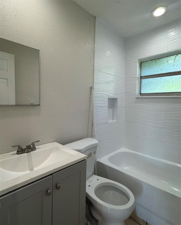 A bathroom features a gray vanity, a white toilet, and a tiled tub-shower combination — 10022 N LANTANA AVENUE UNIT A, TAMPA, FL