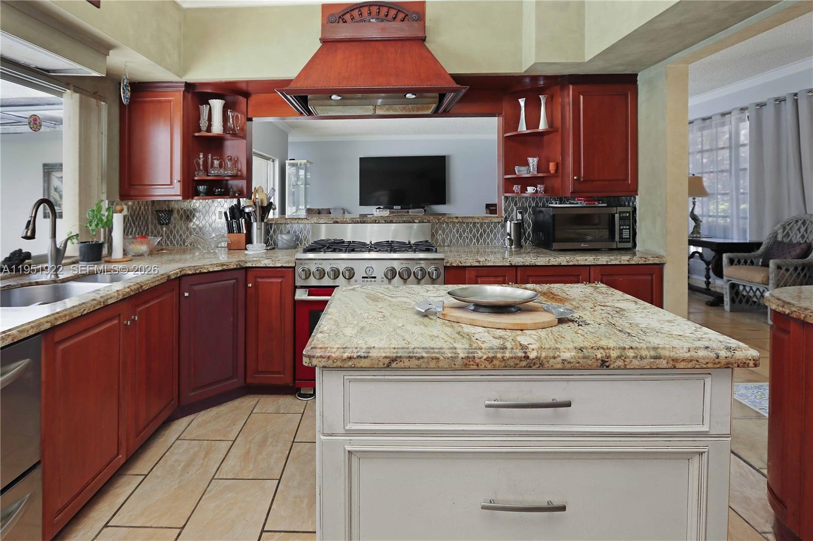 A kitchen features cherry wood cabinets, granite countertops, a central island, and a gas range — 910 N 14th Ct, Hollywood FL 33020, HOLLYWOOD, FL