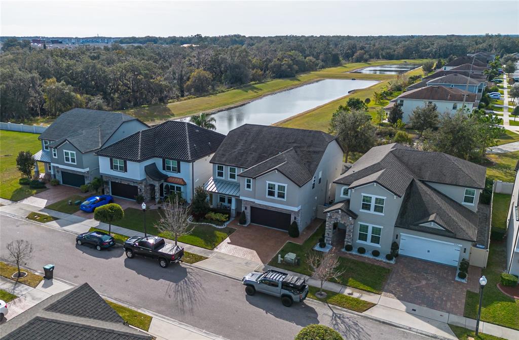An aerial view shows a row of suburban houses with driveways facing a street and pond — 3310 STONEWYCK STREET, ORLANDO, FL