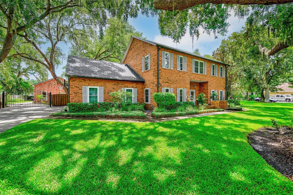 A two-story brick house with a large green lawn and mature trees in the yard — 807 CENTERBROOK DRIVE, BRANDON, FL