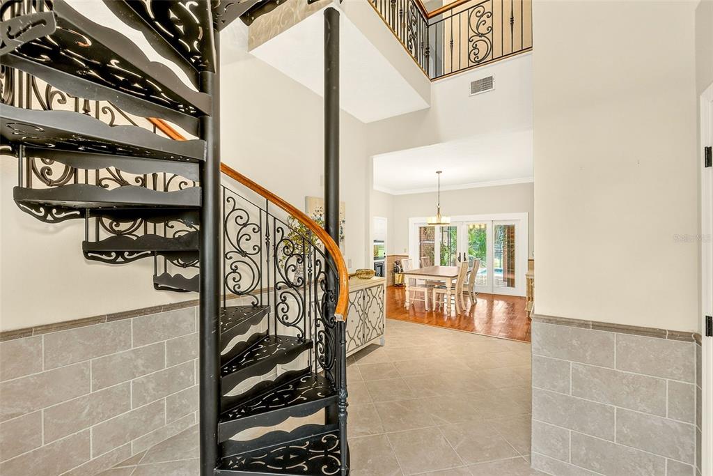 A black metal spiral staircase stands in a tiled foyer leading to a dining area — 807 CENTERBROOK DRIVE, BRANDON, FL