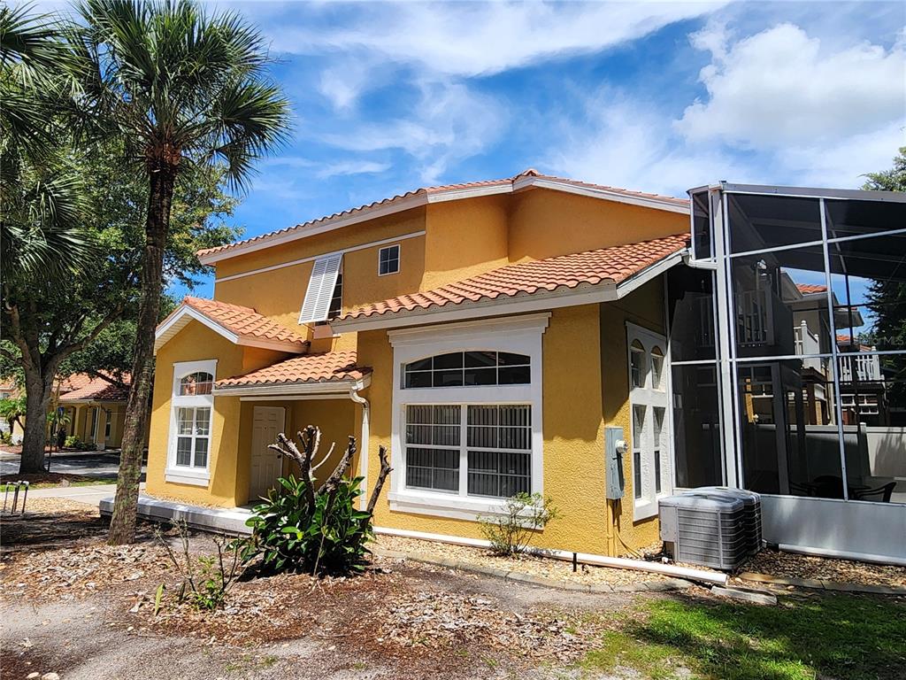 A two-story yellow stucco house with a tile roof and an attached screened-in patio — 1013 PARK RIDGE CIRCLE, KISSIMMEE, FL