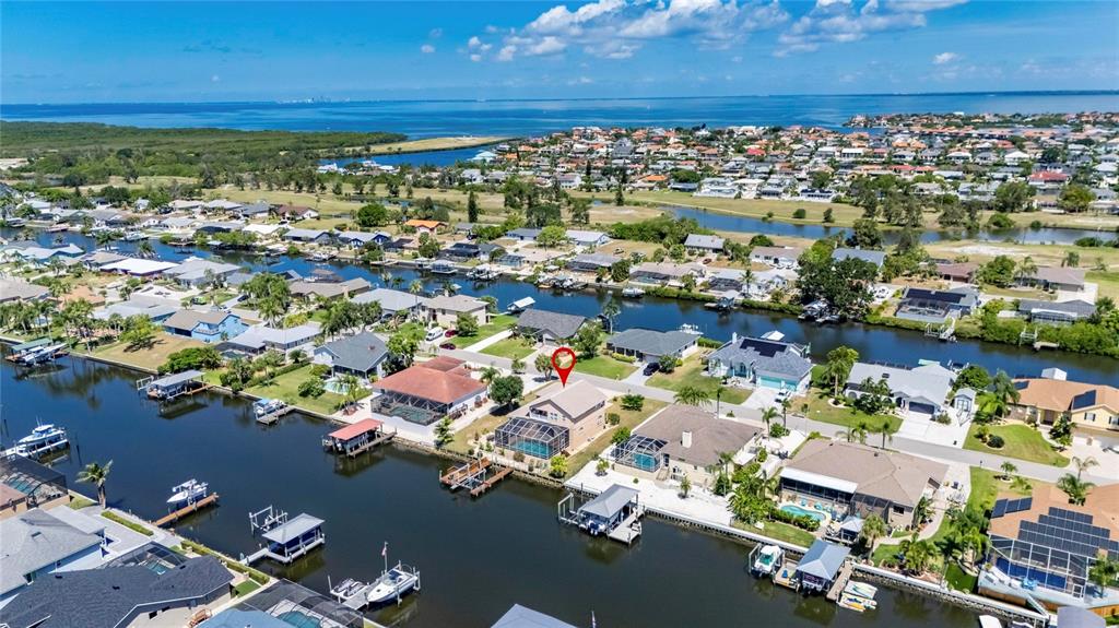 An aerial view shows a tan suburban house with a three-car garage near a canal — 830 GOLF ISLAND DRIVE, APOLLO BEACH, FL