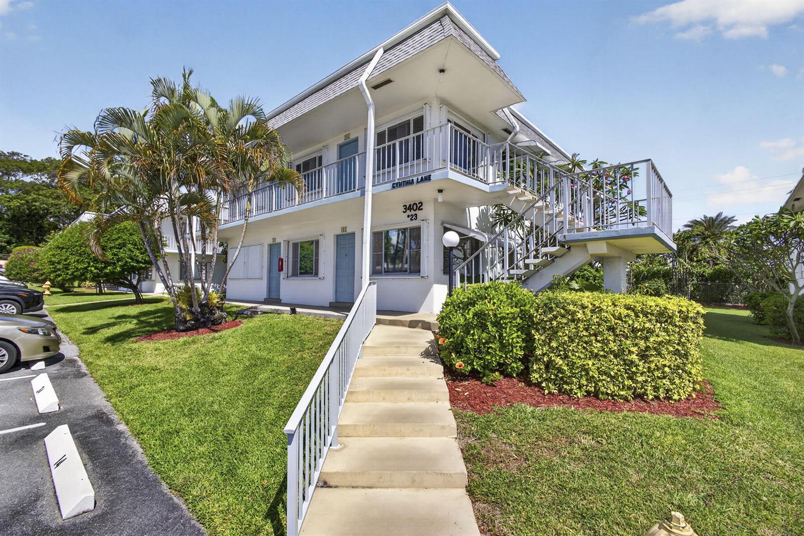 A two-story apartment building with exterior stairs and a concrete walkway on a sunny day — 3402 Cynthia Lane # 201, FL 33461, FL