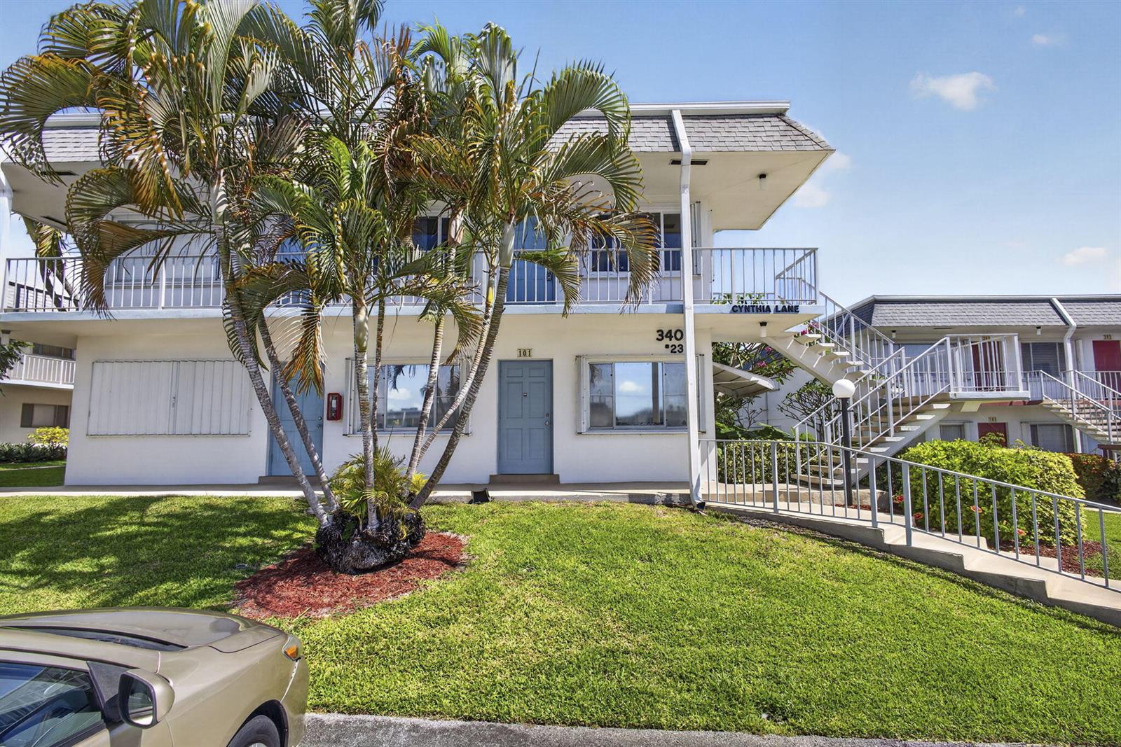 A two-story apartment building exterior features a palm tree, a staircase, and a lawn — 3402 Cynthia Lane # 201, FL 33461, FL