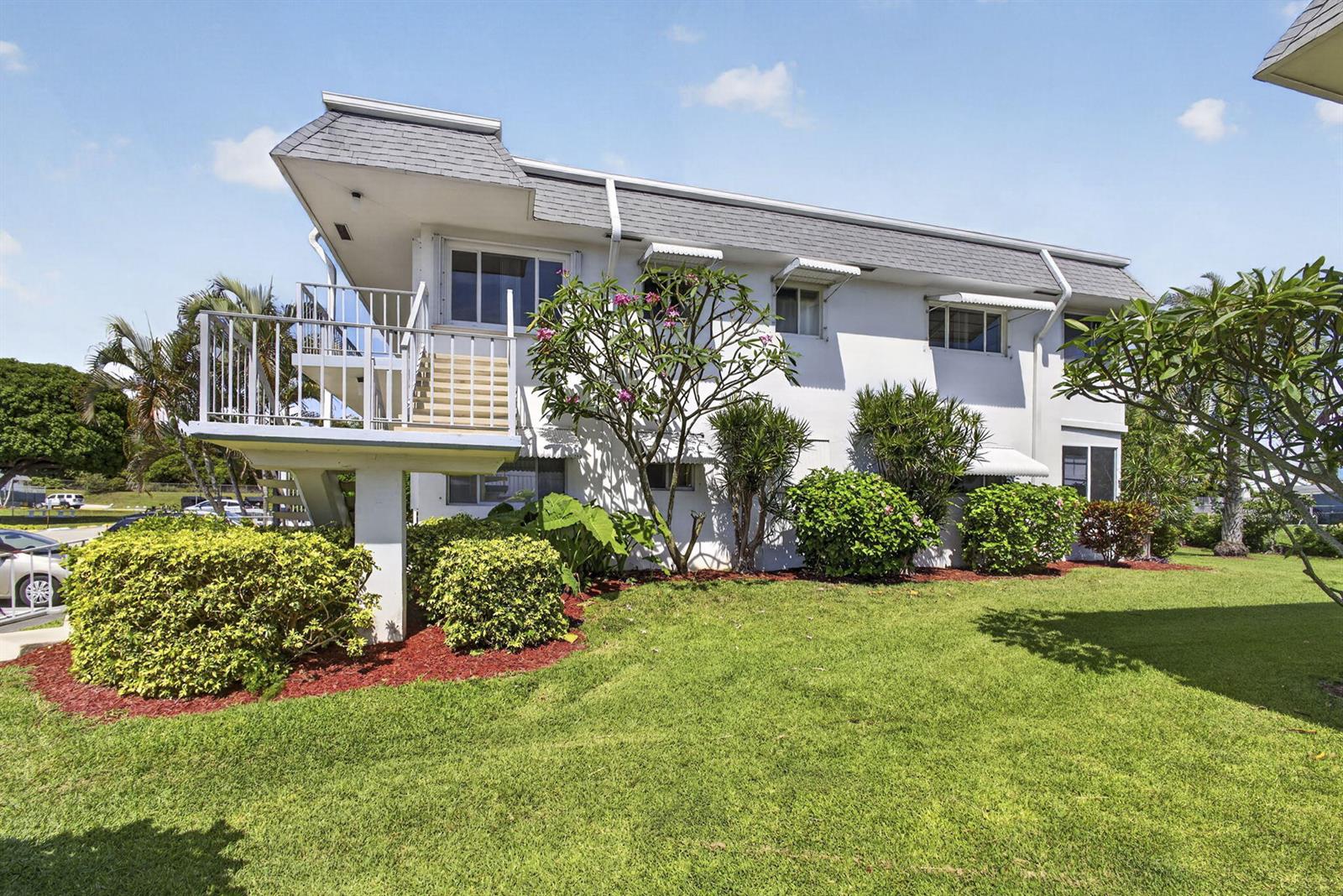 A two-story white apartment building features an exterior staircase leading to a second-floor balcony — 3402 Cynthia Lane # 201, FL 33461, FL