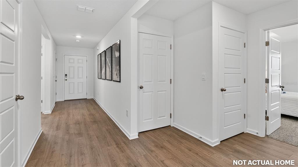 This is a rendering of a hallway with white doors, light wood flooring, and wall art — 4 SENTINEL COURT, PALM COAST, FL