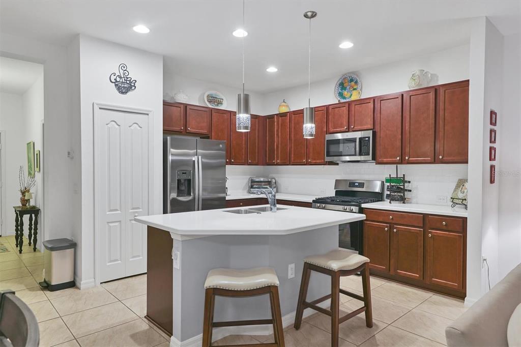 A kitchen features dark wood cabinets, white countertops, a central island, and stainless steel appliances — 317 ACERNO DRIVE, NOKOMIS, FL