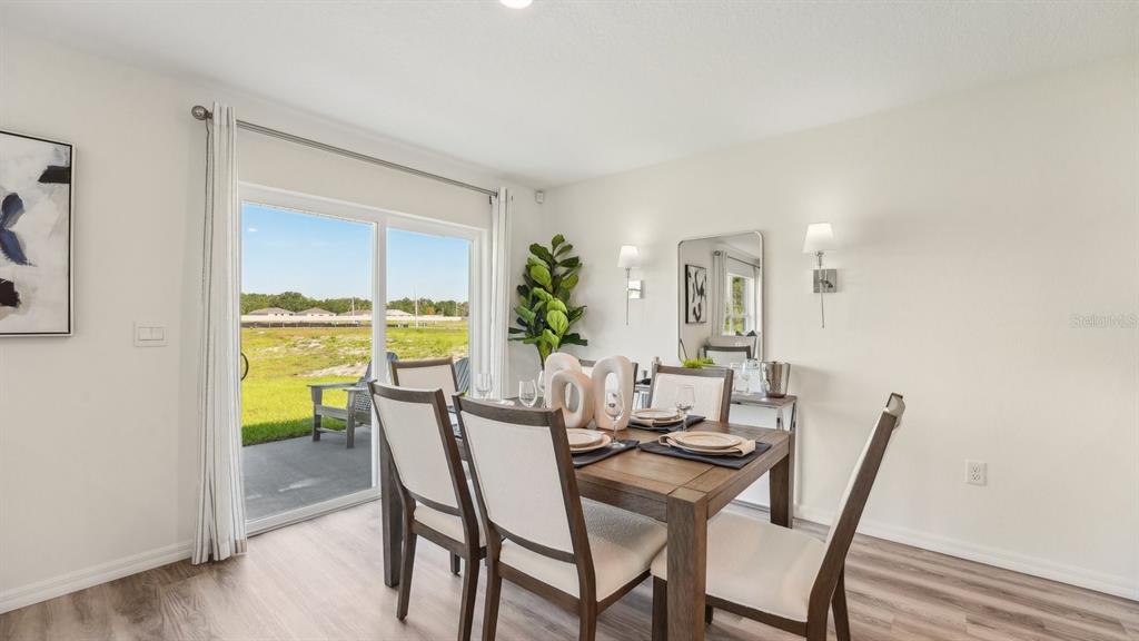 A dining room features a wooden table, four chairs, and a sliding glass door — 8753 TRIUMPH CIRCLE, WILDWOOD, FL