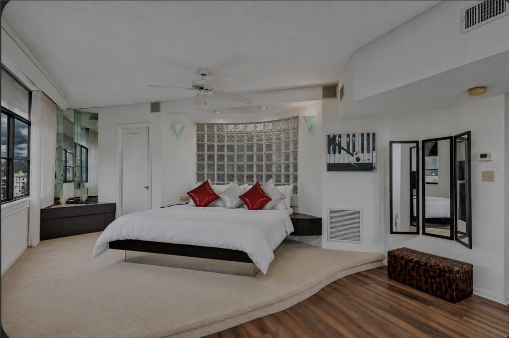 A bedroom features a raised carpeted platform, a glass block headboard, and a floating bed — 602 LIME AVENUE UNIT 203, CLEARWATER, FL