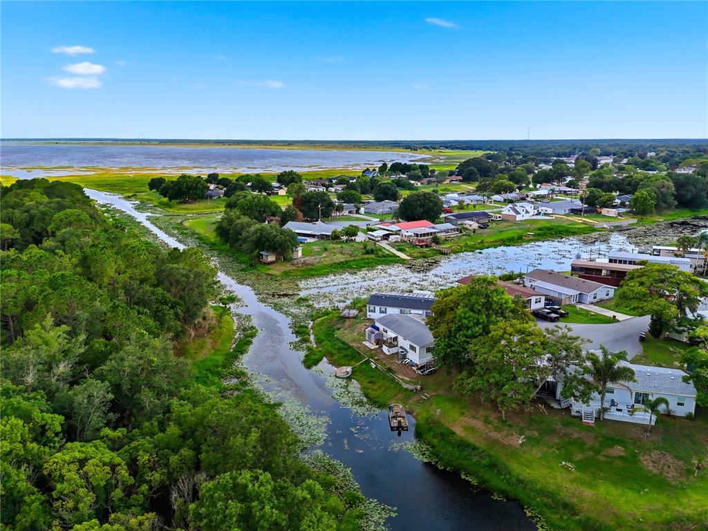 An aerial view shows a waterway winding through a residential neighborhood near a large lake — 338 1ST AVENUE N, LAKE WALES, FL