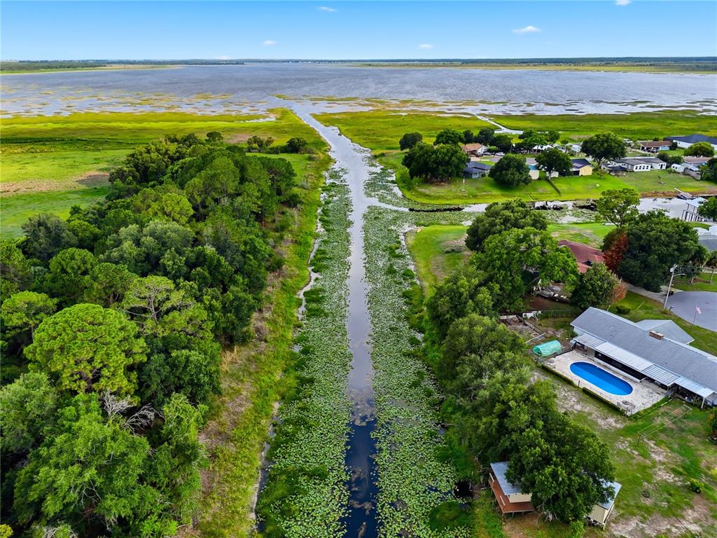 An aerial view shows a narrow canal leading into a large lake near residential homes — 338 1ST AVENUE N, LAKE WALES, FL